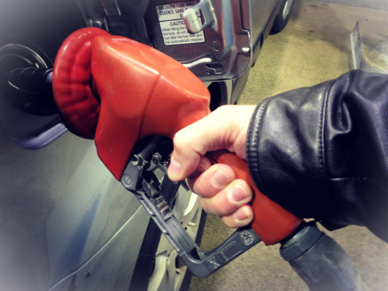 hand pumping gas into car with nozzle